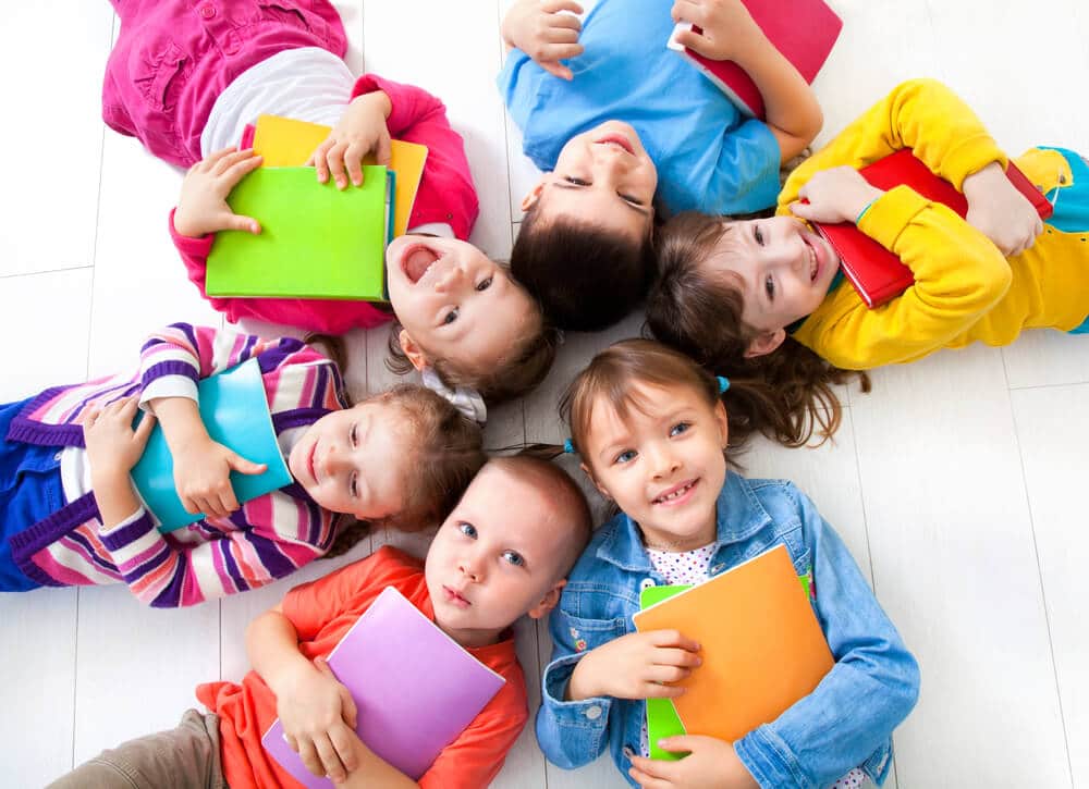 Bild zeigt 6 Kinder auf dem Rücken liegend und lachend