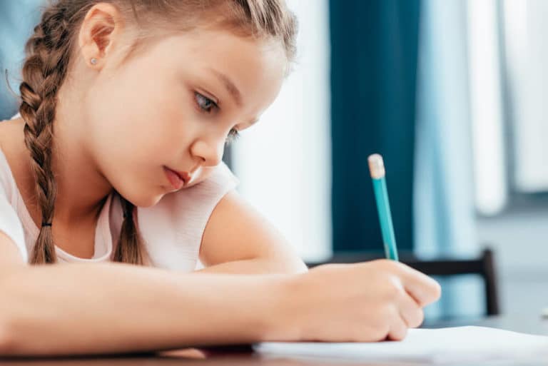 Bild zeigt Kind schreibend mit einem Stift.